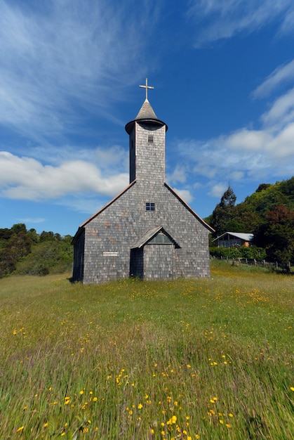 Vertikale Aufnahme einer Kirche in einem Grasfeld unter einem blauen Himmel