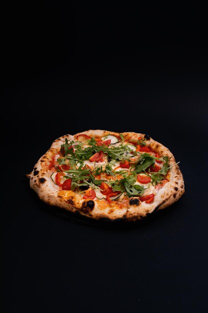 Vertikale Aufnahme einer köstlichen Pizza auf einer schwarzen Oberfläche
