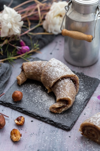 Vertikale Aufnahme einer rohen veganen Rolle aus Haselnüssen auf einer lila Grunge-Tischplatte