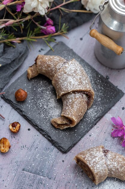 Vertikale Aufnahme einer rohen veganen Rolle aus Haselnüssen auf einer lila Grunge-Tischplatte