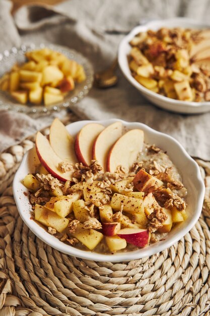 Vertikale Aufnahme einer Schüssel Brei mit Müsli und Nüssen und Apfelscheiben auf einem Tisch