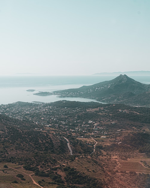 Vertikale Aufnahme einer Stadt und eines Berges nahe der Küste in einer der griechischen Inseln