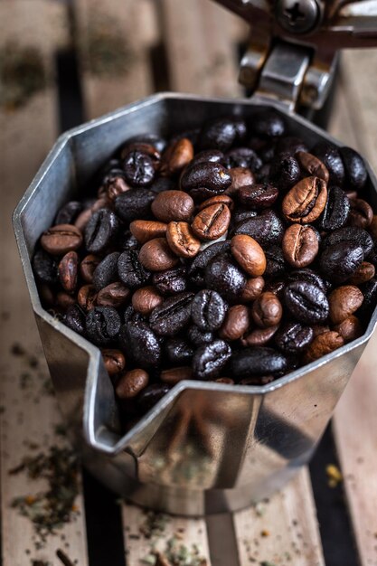 Vertikale Aufnahme eines Behälters voller Kaffeebohnen auf einer Holzoberfläche