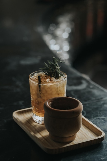 Vertikale Aufnahme eines erfrischenden Cocktails mit Rosmarin auf einem Holztablett