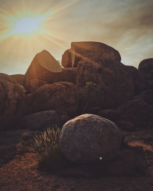 Kostenloses Foto vertikale aufnahme eines felsens mit der sonne, die in den himmel scheint