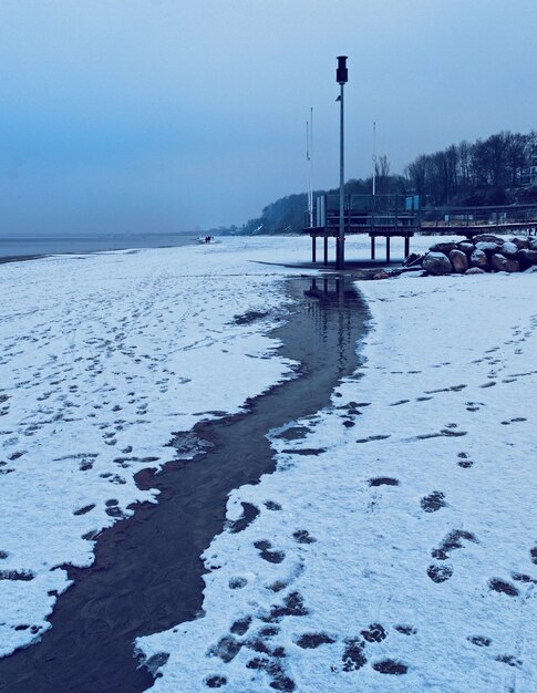 Vertikale Aufnahme eines Flusses, der am frühen Morgen in einem schneebedeckten Gebiet fließt