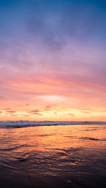 Vertikale Aufnahme eines Gewässers mit dem rosa Himmel während des Sonnenuntergangs. Perfekt für eine Tapete.
