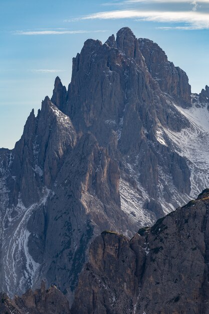 Vertikale Aufnahme eines herrlichen Gipfels eines Felsens in den italienischen Alpen unter dem bewölkten Sonnenuntergangshimmel