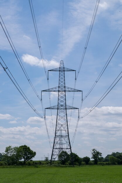 Vertikale Aufnahme eines Hochspannungsmasts, der in einem Feld unter dem Himmel steht