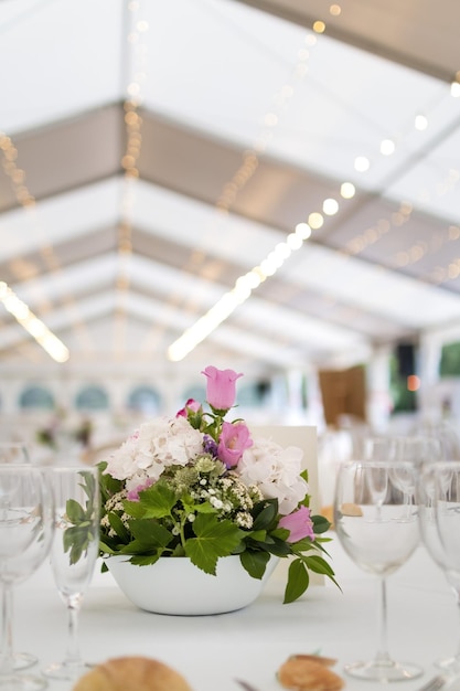 Vertikale Aufnahme eines hübsch dekorierten Tisches in einer für eine Zeremonie vorbereiteten Halle