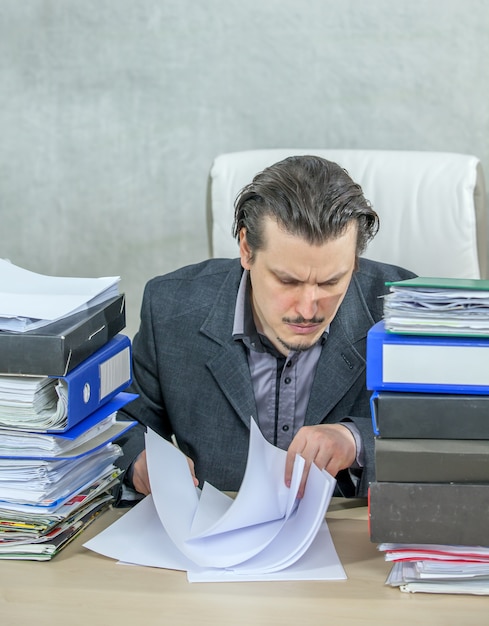 Vertikale aufnahme eines jungen geschäftsmannes, der von seinem büro aus arbeitet - das konzept der harten arbeit