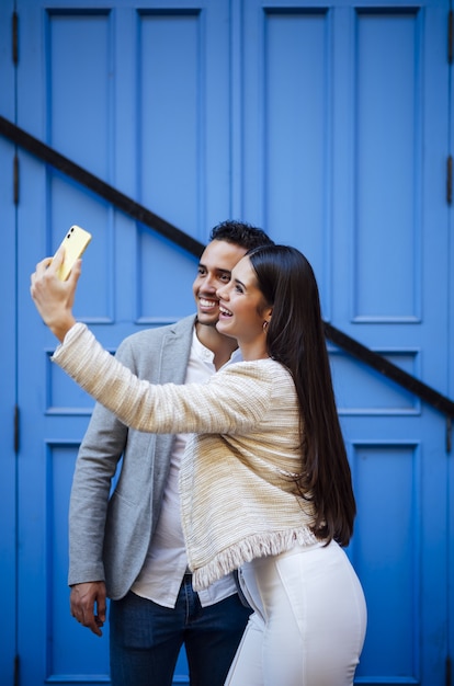 Vertikale Aufnahme eines kaukasischen Liebespaares, das ein Selfie macht