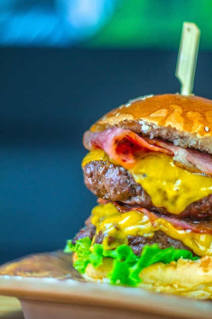 Vertikale Aufnahme eines köstlichen Cheeseburgers mit frischen Zutaten, die mit Spießen befestigt sind