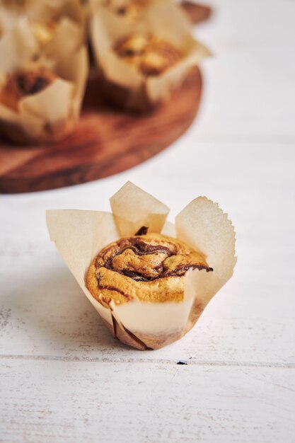 Vertikale Aufnahme eines köstlichen Schokoladenmuffins in der Nähe einer Holzplatte auf einem weißen Teller