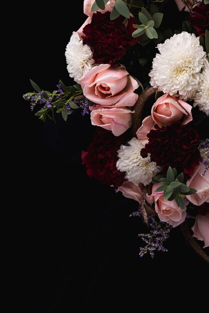 Vertikale Aufnahme eines luxuriösen Straußes von rosa Rosen und weißen, roten Dahlien auf einem schwarzen Hintergrund