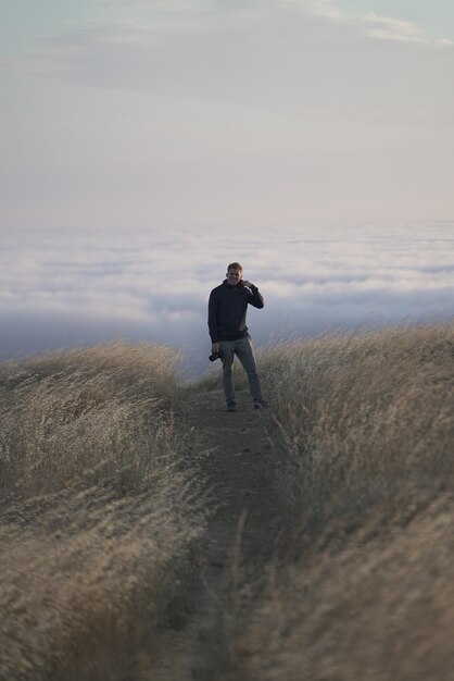 Vertikale Aufnahme eines Mannes, der die Kamera oben auf dem Berg betrachtet. Tam in Marin, CA.