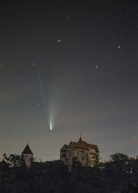 Vertikale Aufnahme eines Neowise-Kometen, der über die Burg Pernstejn in der Tschechischen Republik fliegt