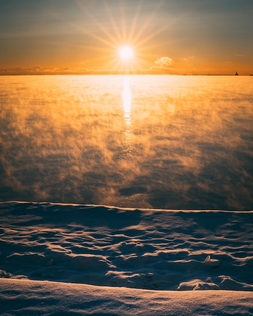 Vertikale Aufnahme eines roten Himmels am Morgen an einem verschneiten Tag