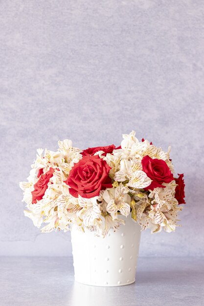 Vertikale Aufnahme eines schönen Blumenstraußes mit roten Rosen und Lilienblumen in einer Schachtel