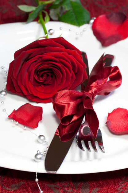 Vertikale Aufnahme eines Tellers mit einer roten Rose auf einem festlichen Tisch