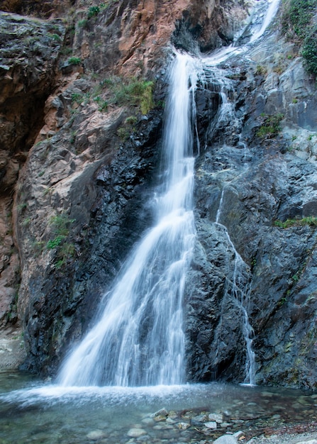 Vertikale Aufnahme eines Wasserfalls, der die Felsen herunterkommt