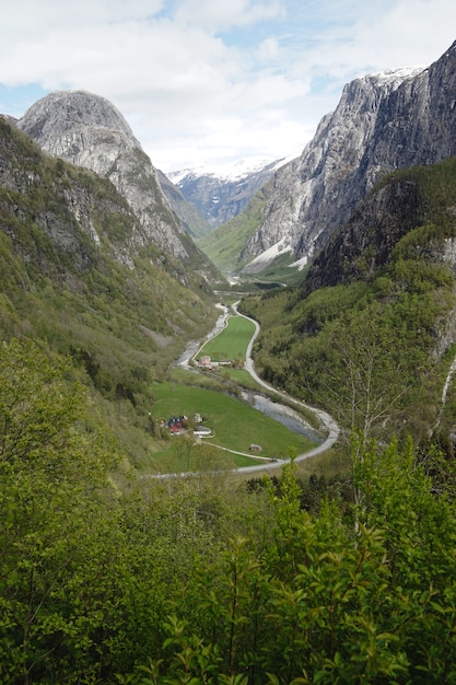 Vertikale Aufnahme eines Weges durch Berge mit grünen Feldern