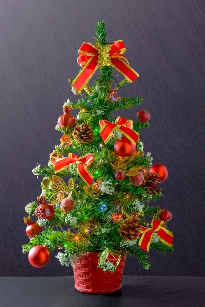 Vertikale Aufnahme eines Weihnachtsbaumes verziert mit roten Bändern und Kugeln