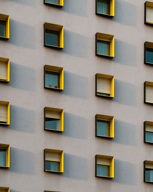 Vertikale Aufnahme eines weißen Gebäudes mit schwarzen und gelben Fensterrahmen