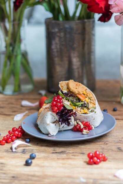 Vertikale Aufnahme eines Wraps mit Gemüse und Reis, dekoriert mit Beeren