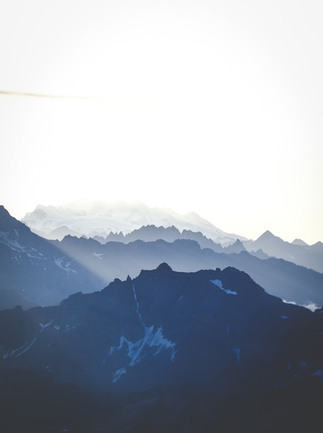 Vertikale Aufnahme von Bergen unter einem hellen Himmel