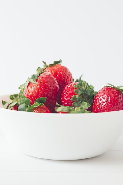 Vertikale Aufnahme von frischen leckeren Erdbeeren in einer weißen Schüssel