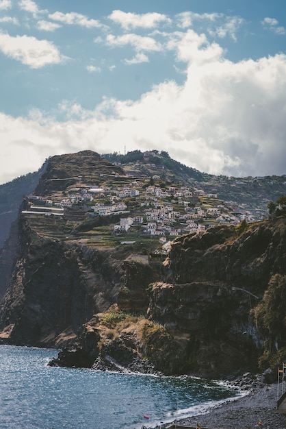 Vertikale Aufnahme von Gebäuden auf dem Berg unter einem blauen Himmel in Funchal, Madeira, Portugal.