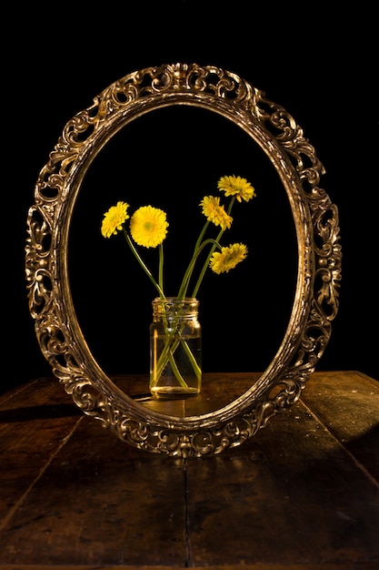 Kostenloses Foto vertikale aufnahme von gelben blumen in einem glas, das auf dem spiegel reflektiert wird