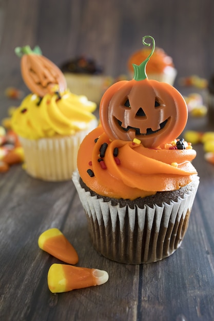 Vertikale Aufnahme von Halloween-Cupcakes mit bunten gruseligen Belägen auf dem Tisch