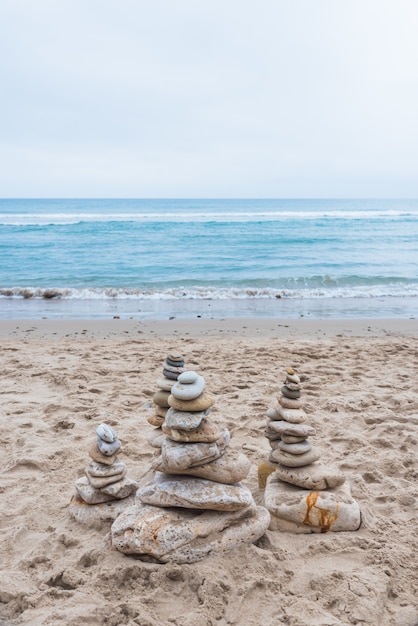 Kostenloses Foto vertikale aufnahme von kieselsteinen, die in einer balance am strand aufeinander gestapelt sind