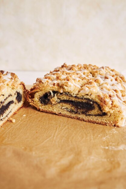 Vertikale Aufnahme von köstlichem Mohnkuchen mit weißer Zuckerglasur auf einem weißen Tisch