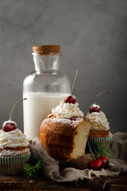 Vertikale aufnahme von köstlichen cupcakes mit puderzucker und einer kirsche mit milch