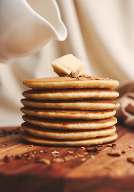 Vertikale Aufnahme von köstlichen Pfannkuchen mit Butter, Feigen und gerösteten Nüssen auf einem Holzteller