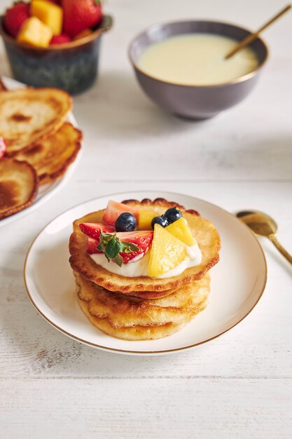 Vertikale Aufnahme von köstlichen Pfannkuchen mit Früchten auf der Oberseite beim Frühstück