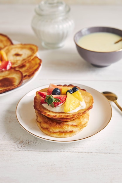 Vertikale Aufnahme von köstlichen Pfannkuchen mit Früchten auf der Oberseite beim Frühstück