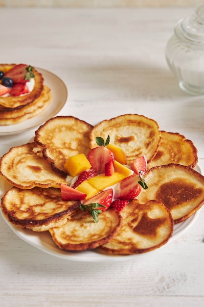 Kostenloses Foto vertikale aufnahme von köstlichen pfannkuchen mit früchten auf einem weißen holztisch