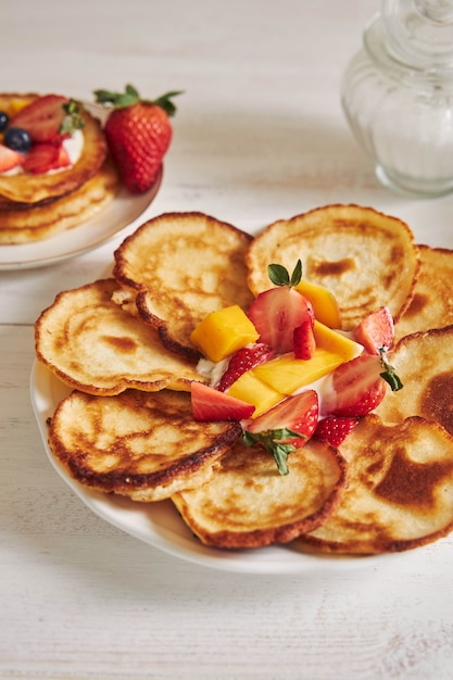 Vertikale Aufnahme von köstlichen Pfannkuchen mit Früchten beim Frühstück