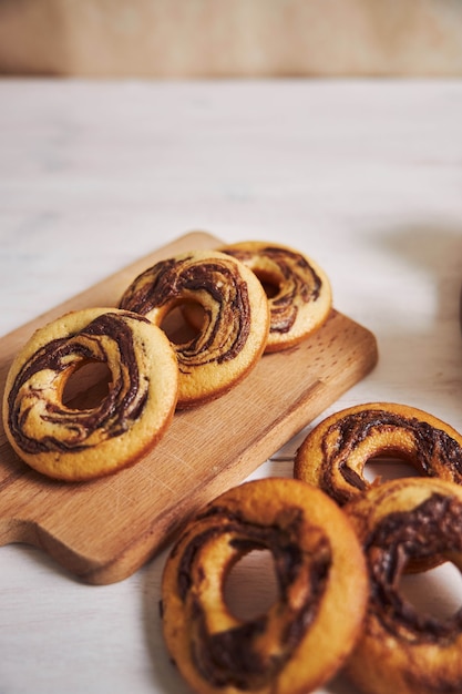 Vertikale Aufnahme von köstlichen Schokoladenkrapfen auf einer Holzplatte auf einem weißen Tisch