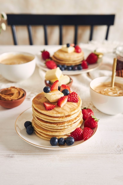 Vertikale Aufnahme von köstlichen veganen Tofu-Pfannkuchen mit bunten Früchten nahe Sirup und Kaffee