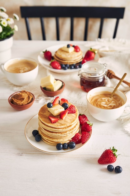 Vertikale Aufnahme von köstlichen veganen Tofu-Pfannkuchen mit bunten Früchten, Sirup und Kaffee