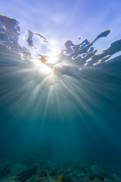 Vertikale Aufnahme von Sonnenstrahlen, die durch den Ozean gleiten und auf beiden Seiten in Samos reflektieren