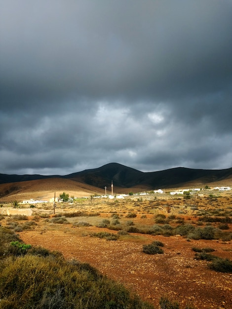 Vertikale Aufnahme von trockenem Tal und Hügeln in den Schatten vor dem stürmischen Wetter in Fuerteventura, Spanien