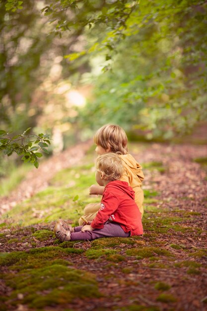 Vertikale Aufnahme von zwei Kindern, die auf einem Hügel sitzen und die Aussicht betrachten