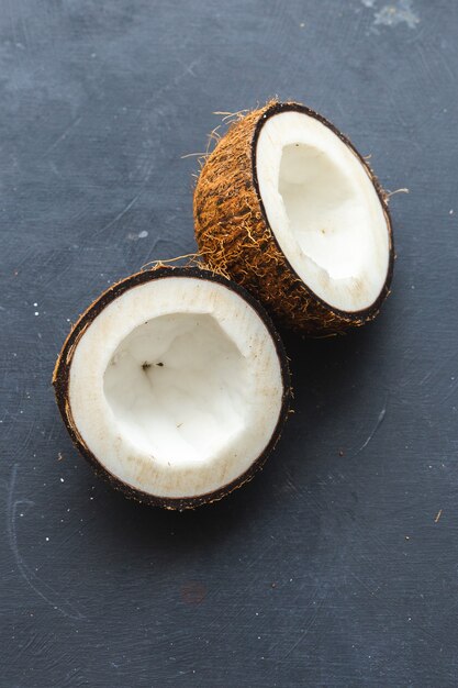 Vertikale Überkopf-Nahaufnahmeaufnahme von geschnittenen Kokosnüssen auf einem Grau
