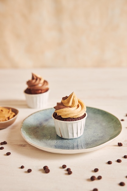 Vertikale flache Fokus-Nahaufnahmeaufnahme des köstlichen Erdnussbutter-Cupcakes mit cremigem Zuckerguss auf Platte